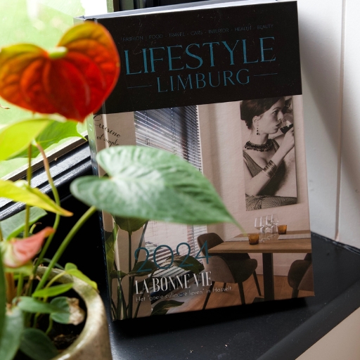 Sfeervolle close-up van een lifestyle boek geopend naast een bloemenvaasje op een zonovergoten vensterbank in La Bonne Vie.